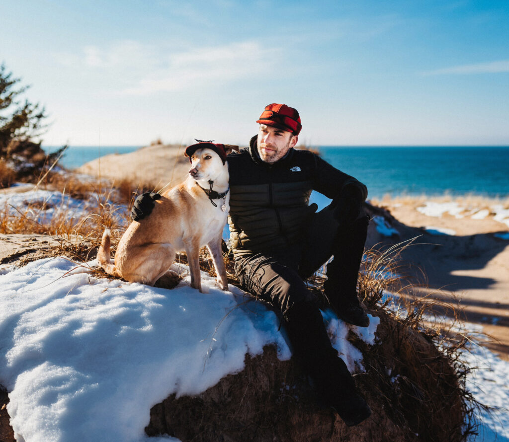 Drew Mason (@drewmason) poses on a beach with his dog (@themittenmutt).