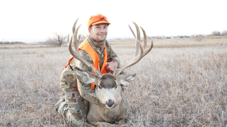 A hunter holding up his buck.