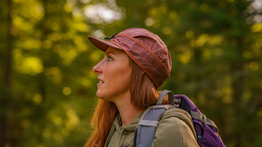 SK The Trail Cap Spring Launch a woman standing in the woods wearing a stormy kromer trail cap