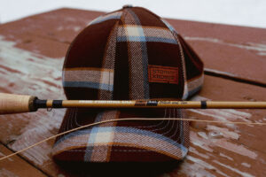 Stormy Kromer cap sitting on a table with a fly fishing pole