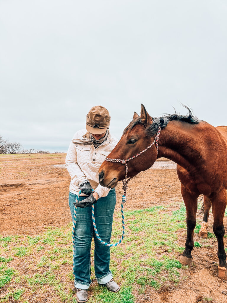 Courtney Lujan wearing a Stormy Kromer cap in a field next to her horse