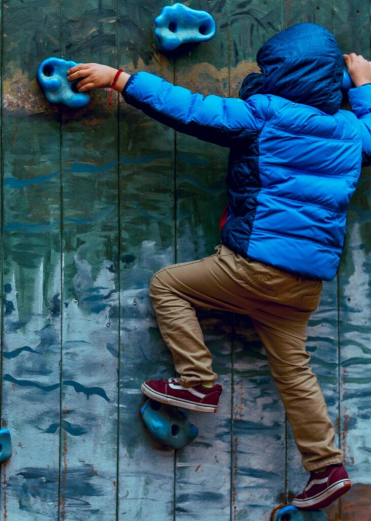 A young boy bouldering outside in the cold